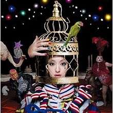 A woman with her head inside of a bird cage, surrounded by circus paraphernalia.