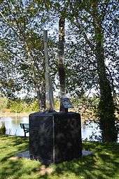 A memorial in a riverside park to singer Kurt Cobain. A plaque attached to the memorial has an image of his face.