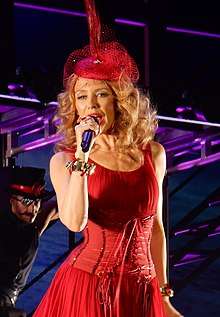 A Caucasian woman wearing a red dress, a red hat while performing on stage