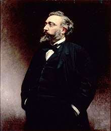 Tinted photo of bearded man with hands in pockets, looking to the left