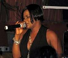 A color photograph of Lady Saw, who is performing live in a microphone.
