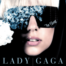 Gaga's face wearing black glasses, whose right side is covered by blue crystals. On the bottom of the left side of the glasses, the word "The Fame" is inscribed in white.
