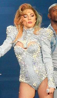 Gaga in a sky blue jewel encrusted leotard with her hair falling on her face performing onstage