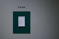 Paper hanging on a white wall with "Poem" written above it