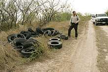 Image of an officer looking at illegally dumped tires on the side of the road.