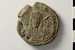 Photo of a round seal, featuring a bust of a bearded, long-haired man holding a spear and a shield