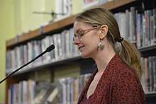 This image shows Irish poet, Leanne O'Sullivan, standing at a microphone in Cork City Library.