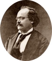 photograph of middle-aged white man with receding dark hair, spectacles and moustache, in semi-profile, facing right