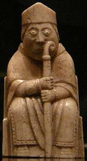 Photograph of an ivory gaming piece depicting a seated bishop