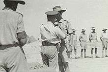 LIEUTENANT-GENERAL SIR LESLIE MORSHEAD, GENERAL-OFFICER COMMANDING A.I.F. (M.E.), PINNING THE RIBBON OF THE ORDER OF THE BRITISH EMPIRE ON LIEUTENANT COLONEL R.J.H. RISSON, COMMANDER ROYAL ENGINEERS, 9TH AUSTRALIAN DIVISION, AT A PARADE AT MAIN HEADQUARTERS OF THE DIVISION, location is North Africa: Western Desert, Western Desert (Egypt), El Alamein Area, El Alamein