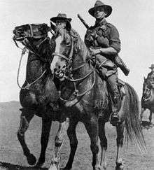 Soldiers mounted on horses with rifles slung.