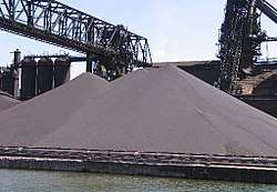 Large gray outdoor piles, surrounded by factory equipment