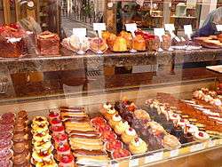Shop display featuring multiple rows of small, colourful pastries.