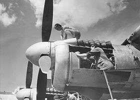 Men in overalls working on piston engines of military aeroplane