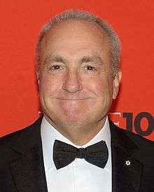A close-up of Lorne Michaels—a middle-aged Caucasian man with white hair wearing a black suit and bowtie—as he smiles