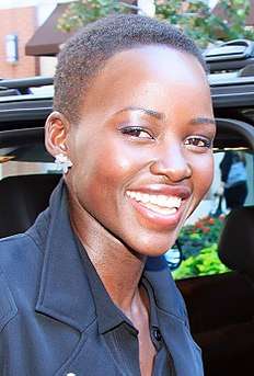 An African American female wearing a navy blue coat is seen smiling.