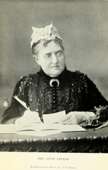 Stern-looking older woman with glasses seated at a desk, writing with a quill pen