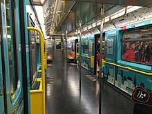 The interior of a R62A subway car used on the 42nd Street Shuttle, which was retrofitted to increase capacity. Almost all of the seats have been removed and replaced with a wallpaper with art on it.