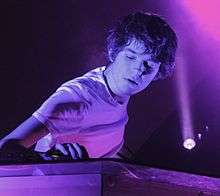 Madeon playing at a DJ booth.