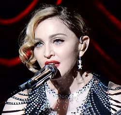 Madonna in a bejeweled dress in front of a microphone