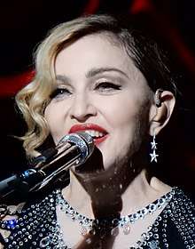 Madonna smiling with a microphone in front of her mouth