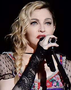 Madonna singing while holding a microphone with her right hand.