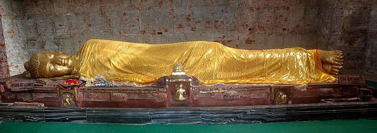 Gold colored statue of man reclining on his right side