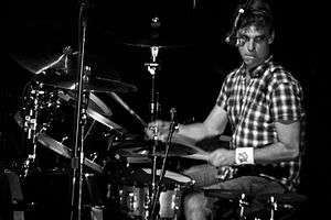 A male drummer, Matt Cameron, seated behind a drumkit of drums and cymbals.