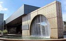 McAllen Public Library has won awards for its beautiful design. This is an image of the fountain in front of the main entrance. The design is a circle inside of a square with water falling down from the top of the circle into a pool.
