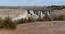 Concrete spillway with bridge running over it, in earth dam