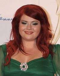 Red-haired woman wearing a green dress with a shiny diamond broach