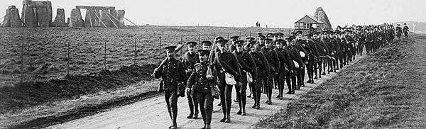 Men in uniform walking past Stonehenge, old picture