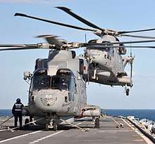 Two AgustaWestland Merlin HM2 of 814 NAS landing on HMS Illustrious during Exercise Joint Warrior near Scotland in 2012. Note the tiger markings on the aircraft noses.
