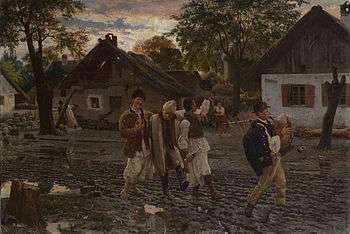 Four men walking through a village in an intoxicated state