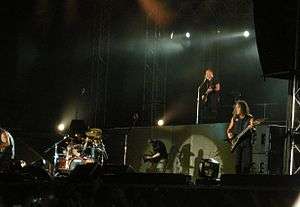 The four band members are shown performing during a concert