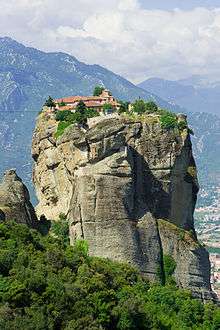 A monastery stands atop a large mountain.