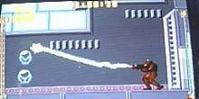 A video game screenshot of a person in a powered exoskeleton firing a beam.