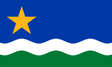 The flag consists of a wide horizontal blue stripe on top, followed by a thin wavy white stripe, followed by a wavy green stripe. There is a five-pointed yellow star in the top left corner.