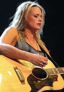 A young woman with long blonde hair playing a guitar