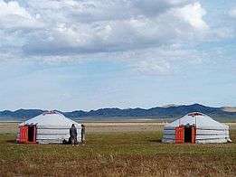 Two yurts, with people outside for scale
