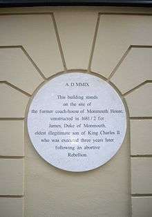  A white plaque on a beige wall noting where Monmouth House stood in Soho Square