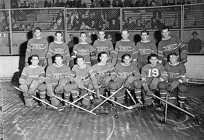 1942 Montreal Canadiens posing for photo on rink. First row of seven players kneeling and second row of seven players standing behind.