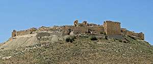 Ruins of the walls of a fortress made of stone on a hill in a desert