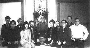 Black-and-white photograph of a group of people kneeling around an elderly Japanese man
