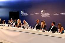The cast and director sitting at a long table