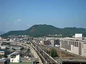 Mt. Shinobu rises from the center of the city of Fukushima. Train tracks can be seen going through a tunnel in the mountain.