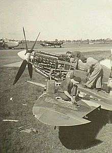 Three men servicing a single-engined military aircraft
