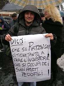 Man holding a placard with Italian writing; translation in caption.