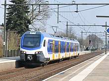 A blue, white and yellow electric train stopped at a station platform