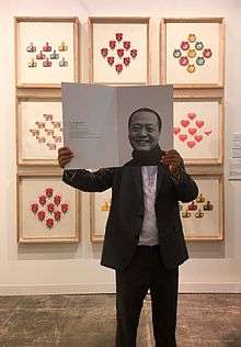 Nan Qi holds up a catalogue featuring himself at his booth at Art Basel Hong Kong 2017